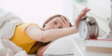 Young woman turning off alarm clock